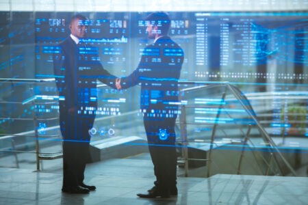 The two traders shake hands in front of a virtual screen